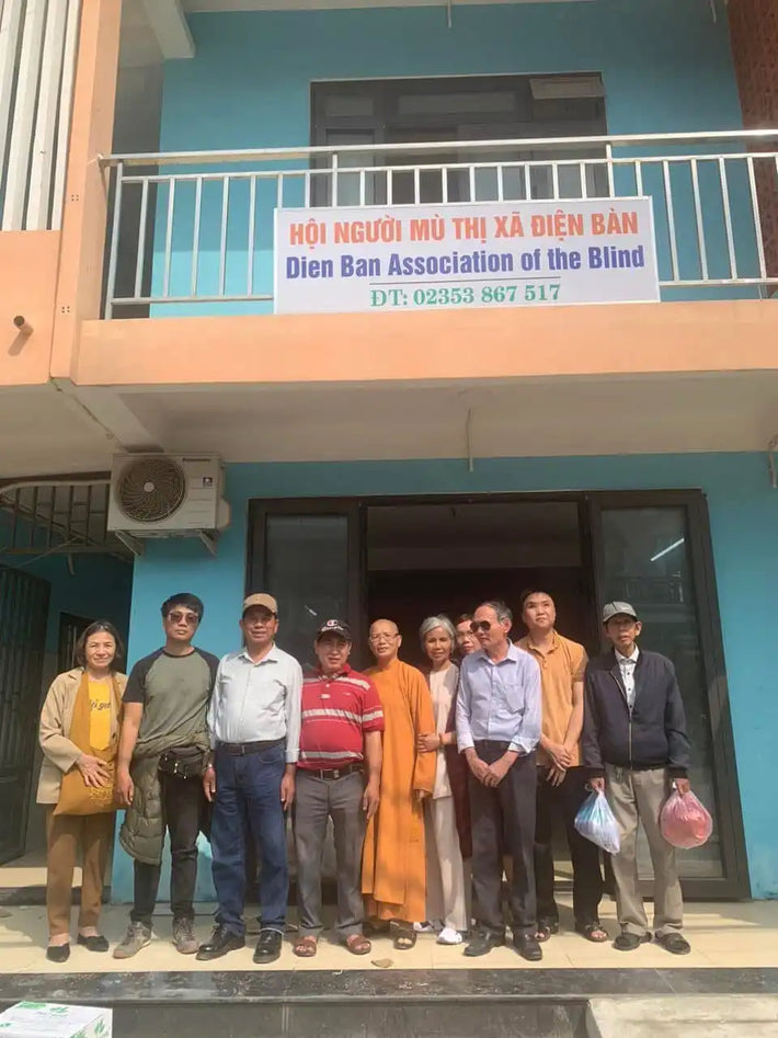 A group of people standing in front of a building with a banner.